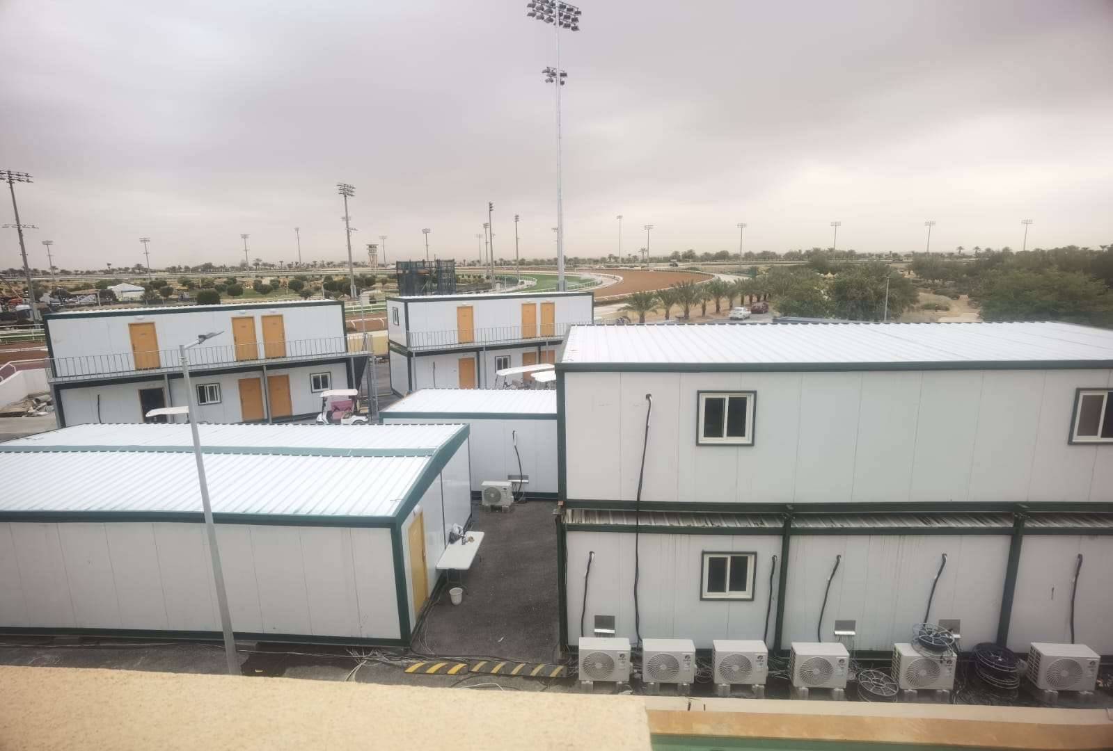 Prefabricated Sandwich Panel Modular Cabins Setup Multi-story sandwich panel prefab modular cabins and porta cabins installed at a site overlooking a racetrack