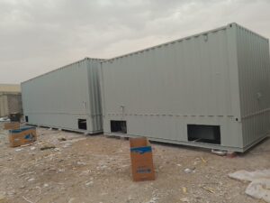 حاويتا شحن معدنيتان كبيرتان باللون الرمادي موضوعتان في موقع ترابي خارجي