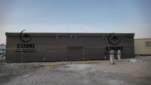واجهة مبنى جاهز أو بركس طويل بتصميم بديل الخشب مع نوافذ زجاجية عريضة وإضاءات سقفية خارجية متميزة.