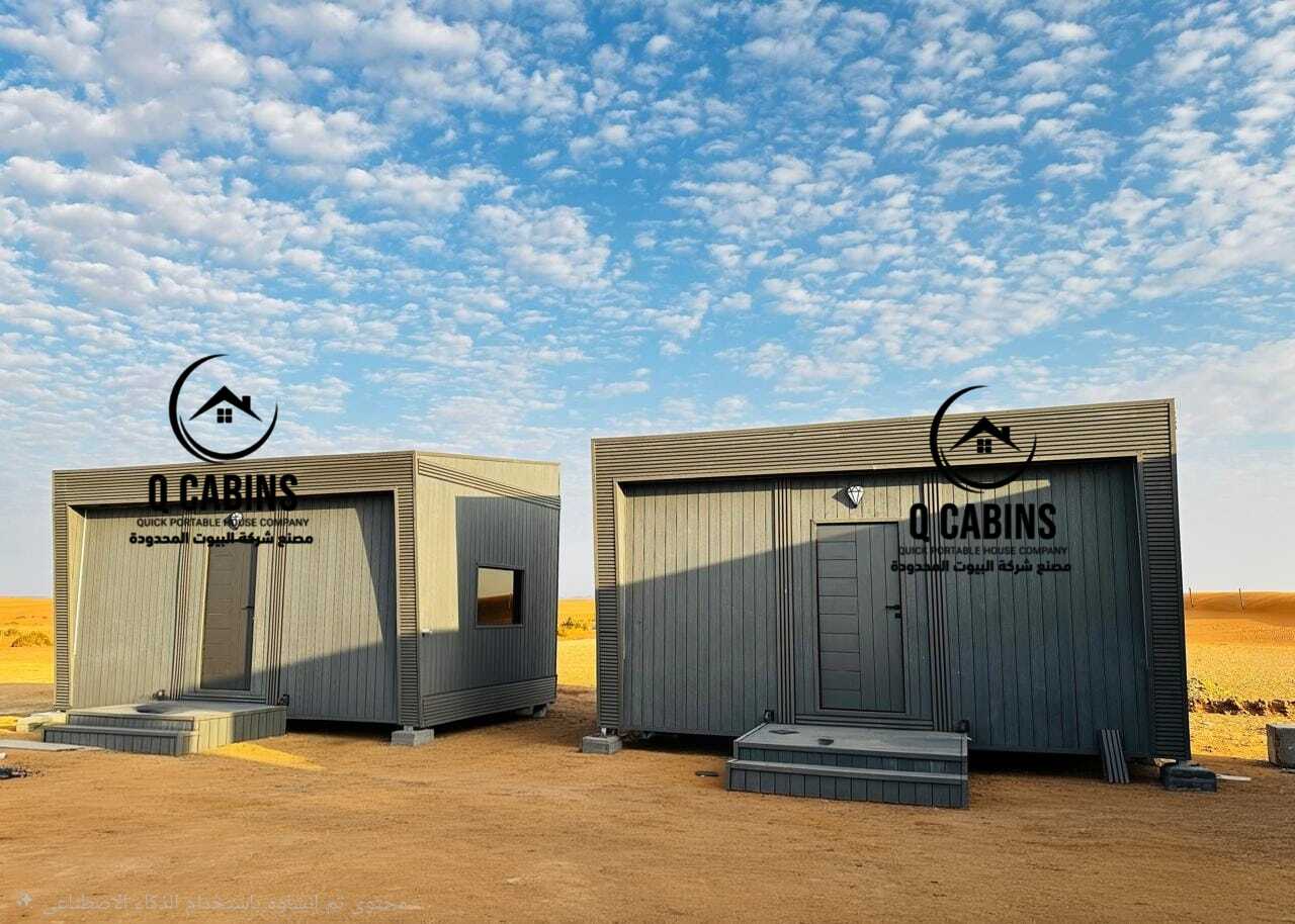 وحدتان من الكابينات والغرف الجاهزة بتشطيب بديل الخشب في موقع تنفيذ صحراوي مفتوح.
