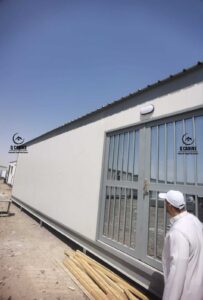 بركس ساندوتش بانل أبيض مزود بنوافذ ذات شبك حماية وقضبان حديدية.