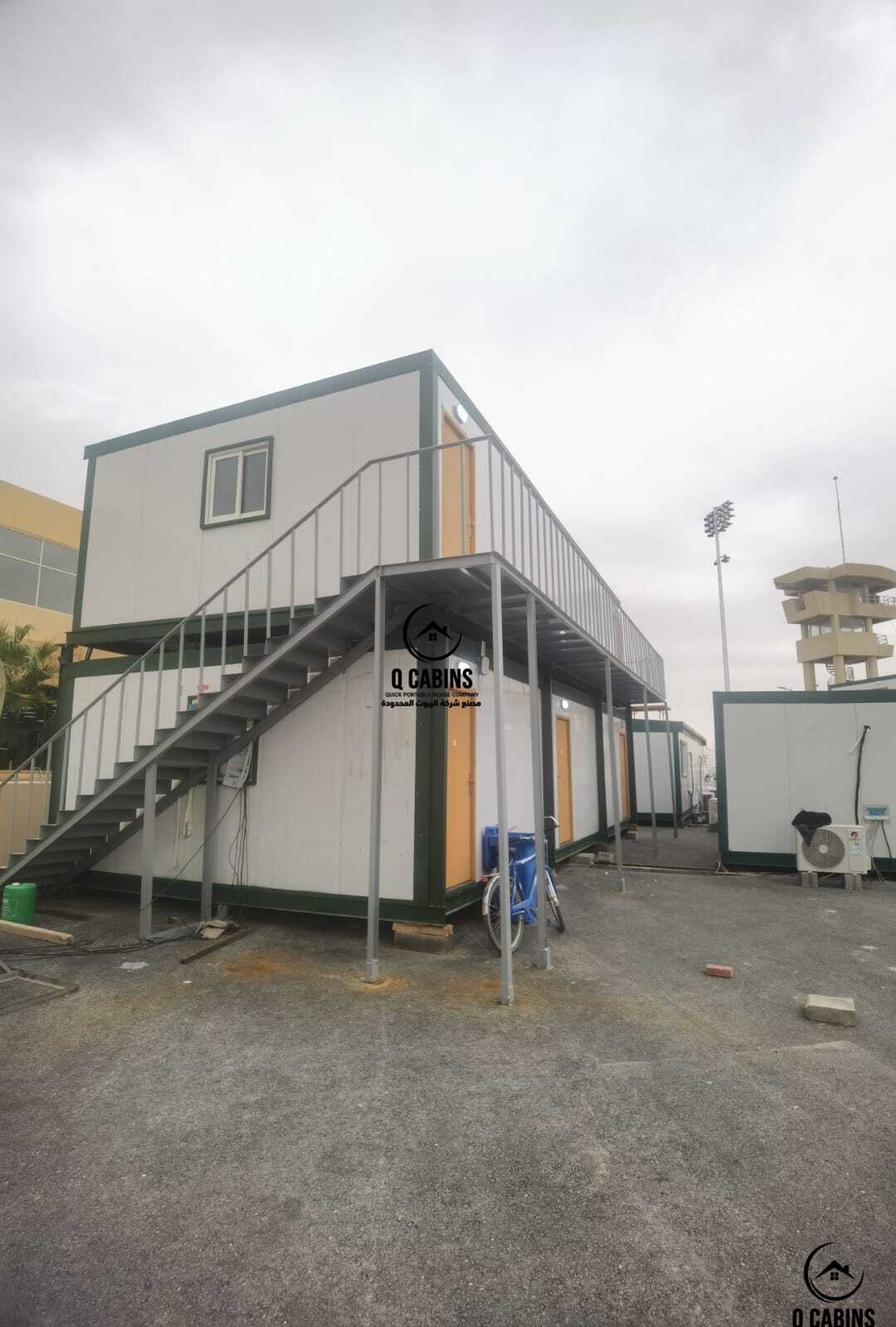 مجمع غرف ساندوتش بانل طابقين مع درج جانبي حديدي للتنقل بين الأدوار.