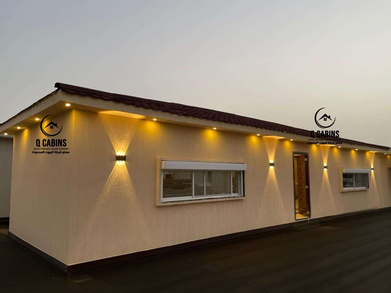 Exterior night view of an illuminated cement board porta cabin with warm LED spotlights.