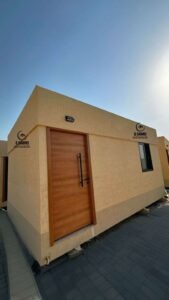 Heavy-duty wooden entrance door on a prefabricated cement board cabin.