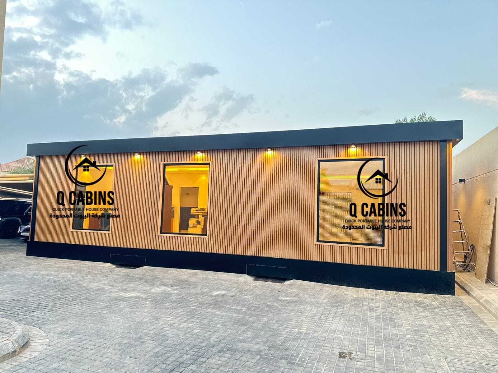 Illuminated glass windows of a premium cladding prefabricated room with exterior warm lights