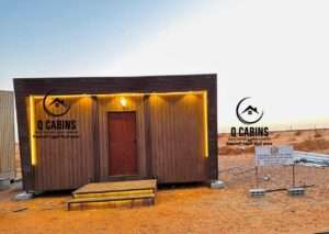Prefabricated house with exterior lighting, glass windows, and warm wood plastic composite cladding