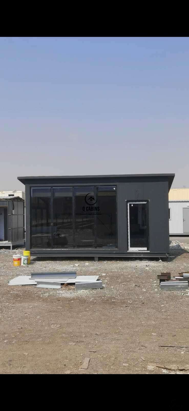 Modern dark grey sandwich panel site office with floor-to-ceiling glass panel facade